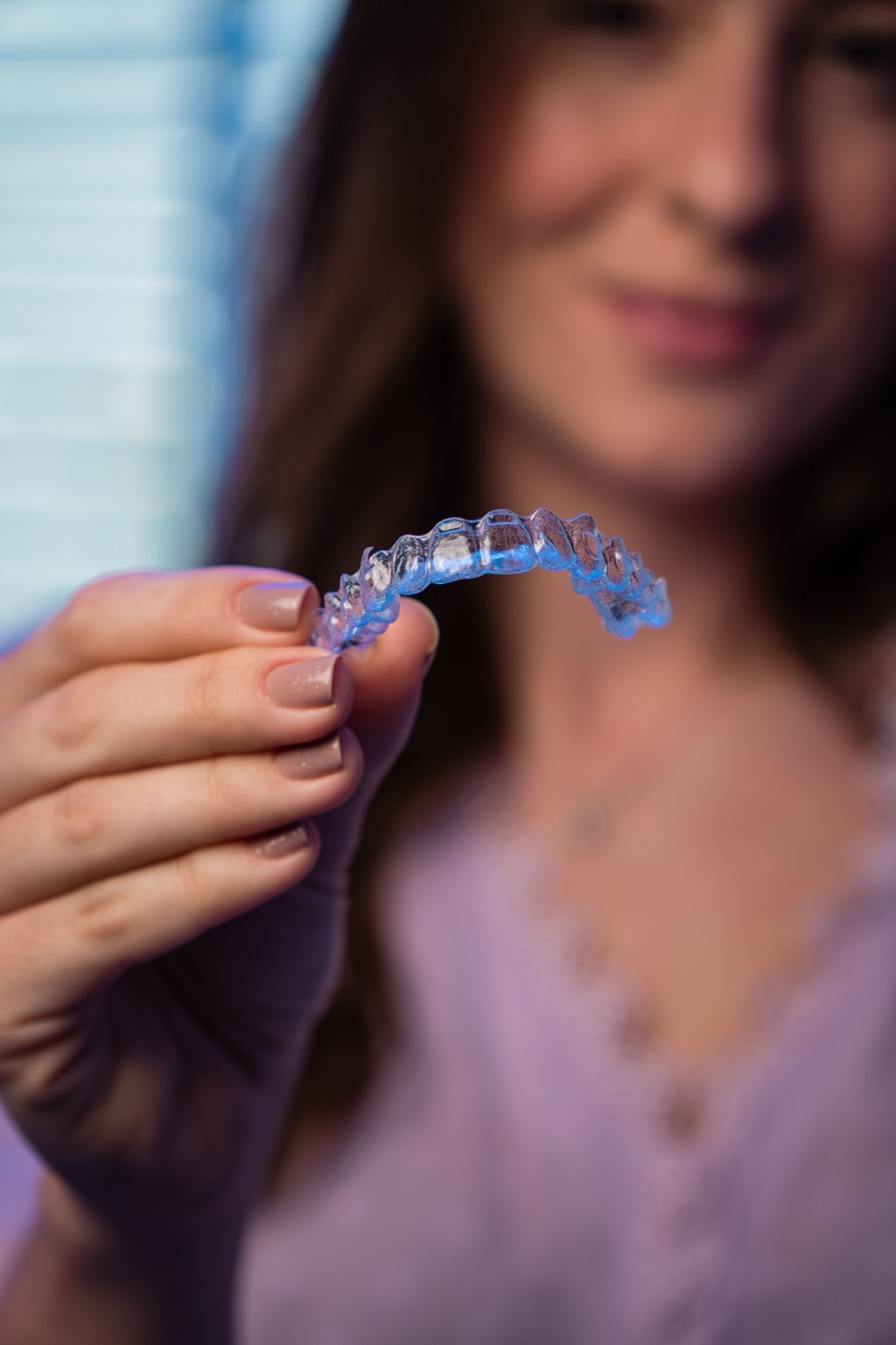 Fotografía ilustrativa de una mujer sosteniendo un alineador transparente